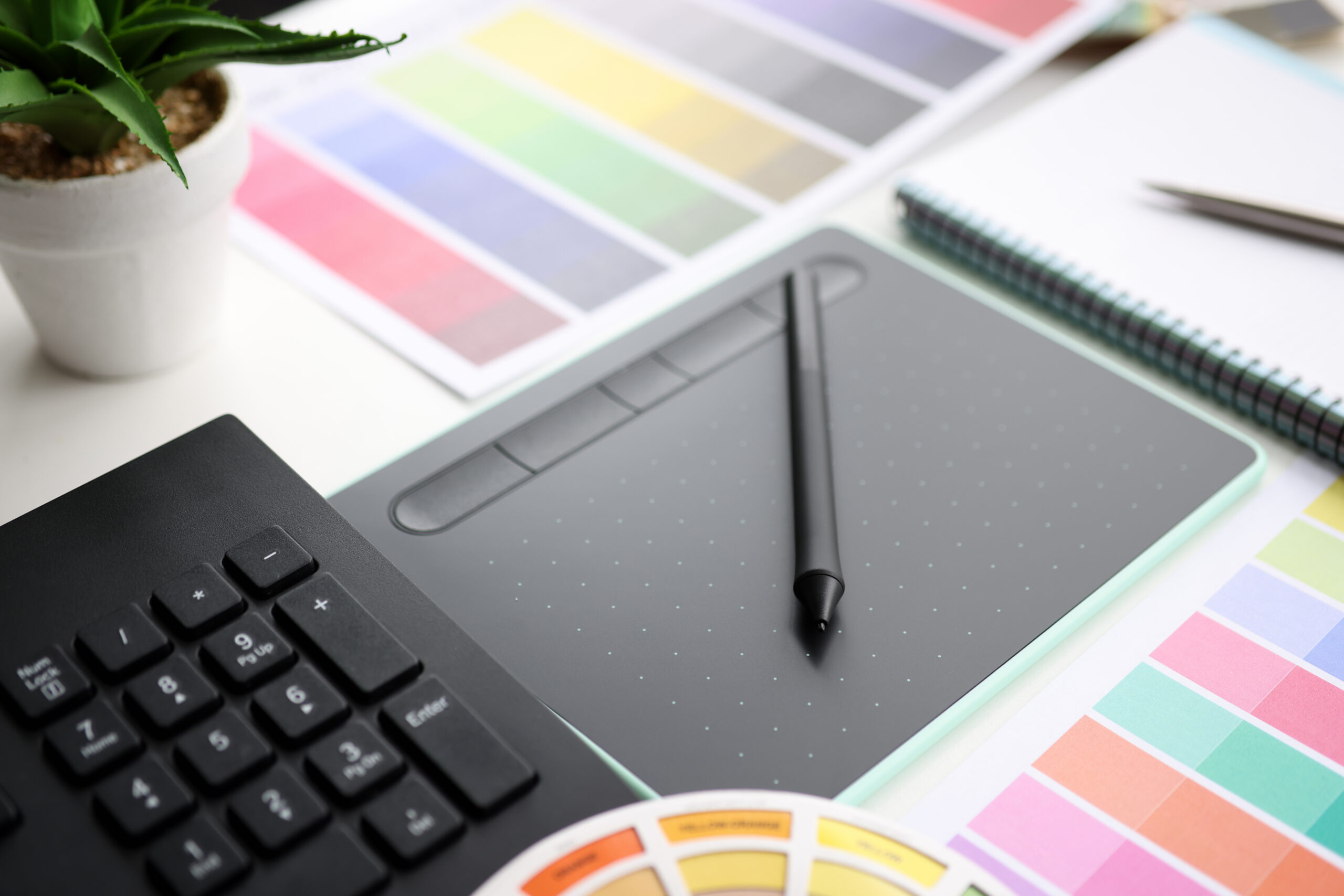Graphic tablet with stylus and color palette on table. Web graphic designer concept